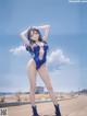 A woman in a blue bathing suit standing on a beach.