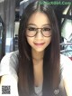 A woman with long black hair wearing glasses. 