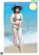 A woman in a blue bikini standing on the beach.