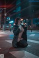 A woman wearing a face mask sitting on the street at night.