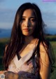 A woman with long brown hair standing in a field.