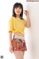 a woman in a yellow shirt and colorful shorts posing for a picture