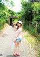 A woman standing on the side of a road holding a plastic bag.