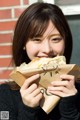 A woman holding a paper bag with a sandwich in it.
