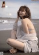 A woman sitting on the beach in a white dress.