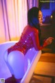A woman in a red latex outfit sitting in a bathtub.